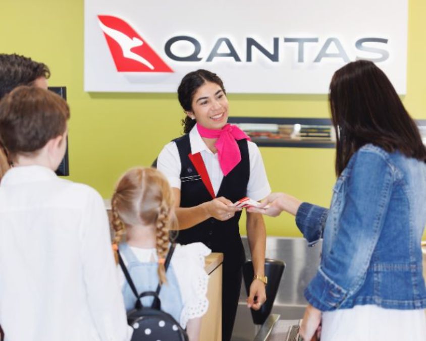 Qantas check-in counter at Longreach Airport with staff assisting passengers during the check-in process